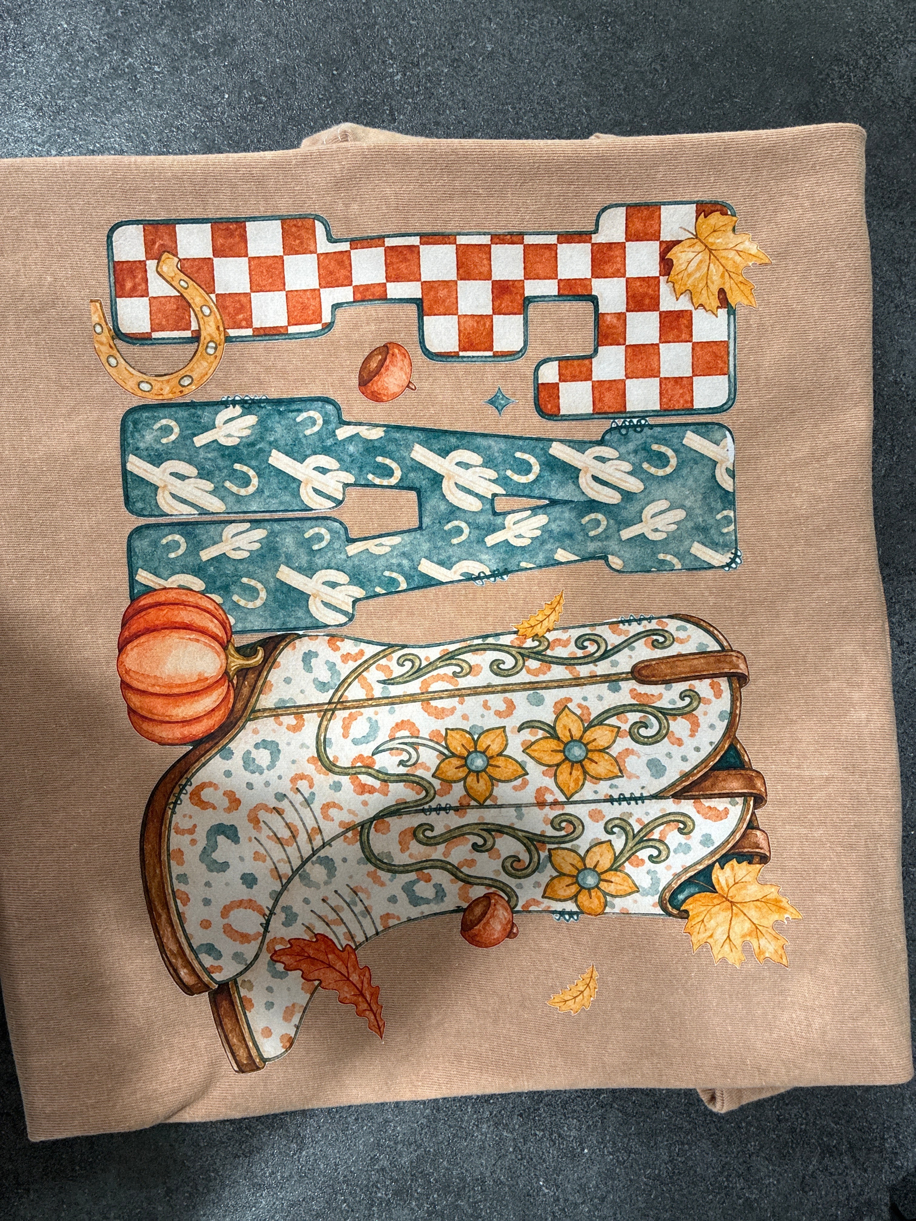 Light brown fall western cowboy boot shirt with checkered letters, pumpkins, and autumn leaves